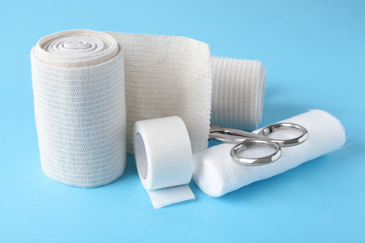 medical-bandage-rolls-sticking-plaster-and-scissors-on-light-blue-background